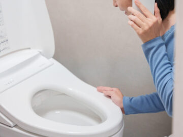 トイレのトラブルで水道業者に電話する女性